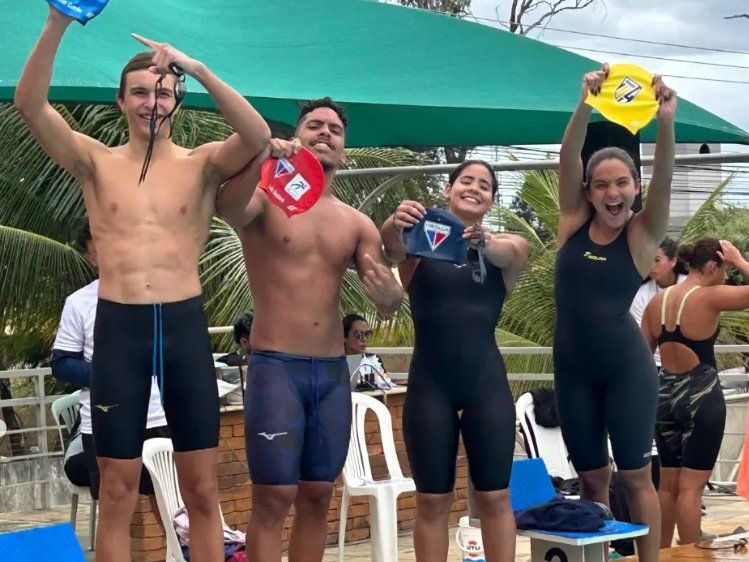 Quarteto do revezamento misto da Raia 4 comemorando à beira da piscina